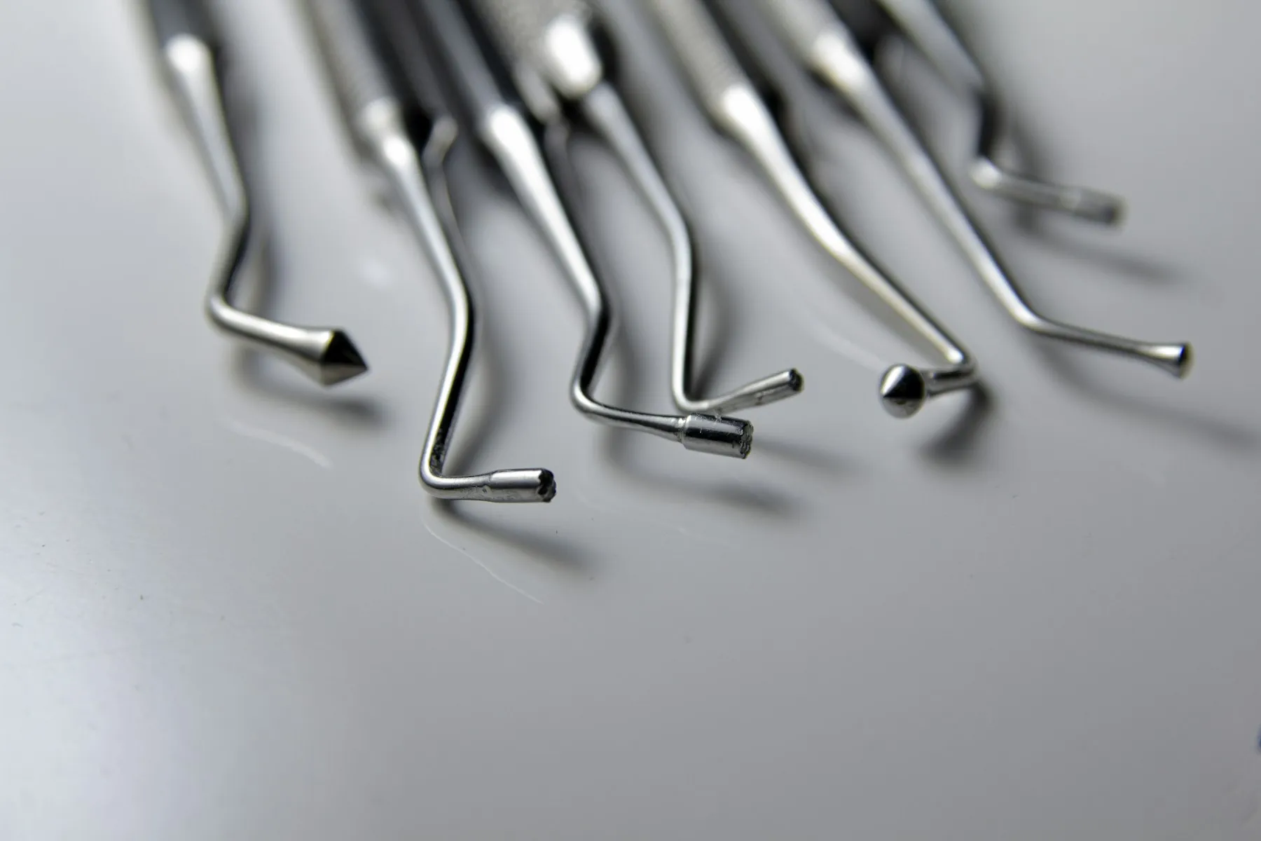 Instrumental dental de precisión — sondas y curetas odontológicas sobre superficie neutra · Consciencia Odontológica, Villa Nueva, Guaymallén, Mendoza